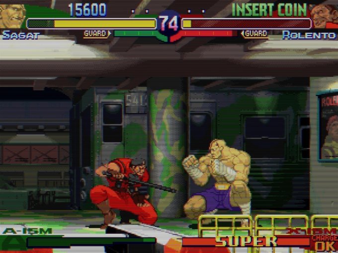 Tela do jogo de uma luta entre Sagat e Rolento, em um cenário de estação de metrô. Ambos os personagens estão abaixados e parados.
