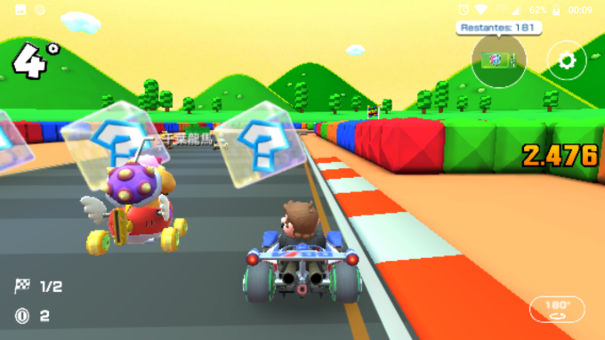 Cena do jogo, com o personagem Mario em um kart em meio a uma corrida, ao lado de outros adversários e em frente a cubos 3D com interrogações dentro