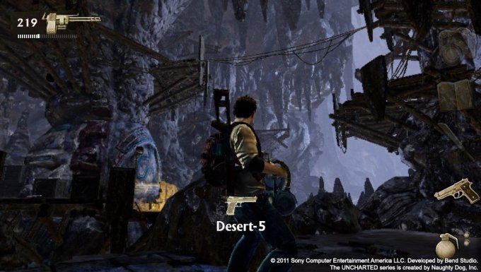 Nathan Drake segurando arma em batalha contra inimigos dentro de uma caverna